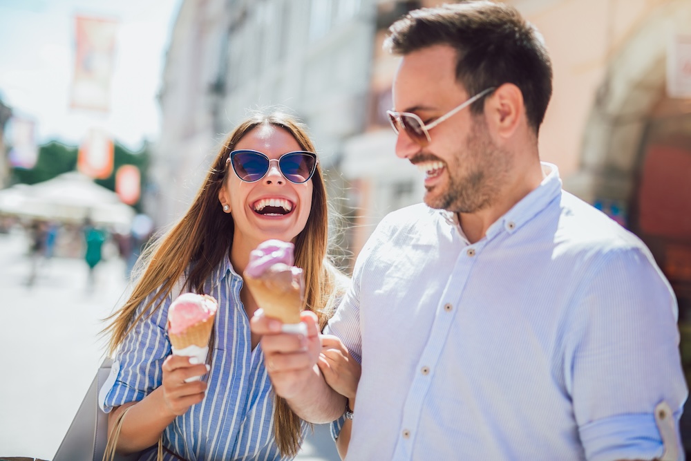 Happy couple having date and eating ice cream after shopping.